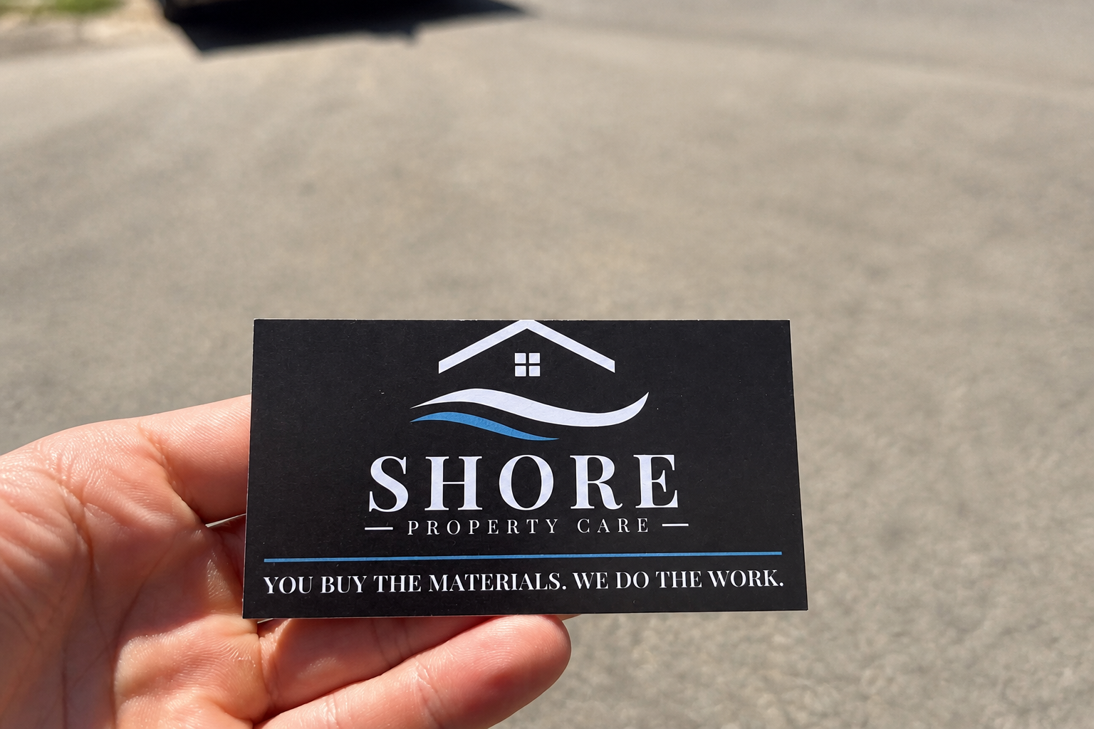 Shore Property Care business card held outdoors